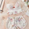 da620fe0-43a7-4ece-8227-19064cbb4d9a Floral lace ruffle-trim bralette with adjustable straps paired with matching floral print sleep shorts on soft tulle backdrop.